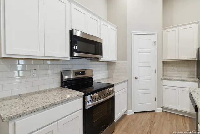 a kitchen with white cabinets and black appliances