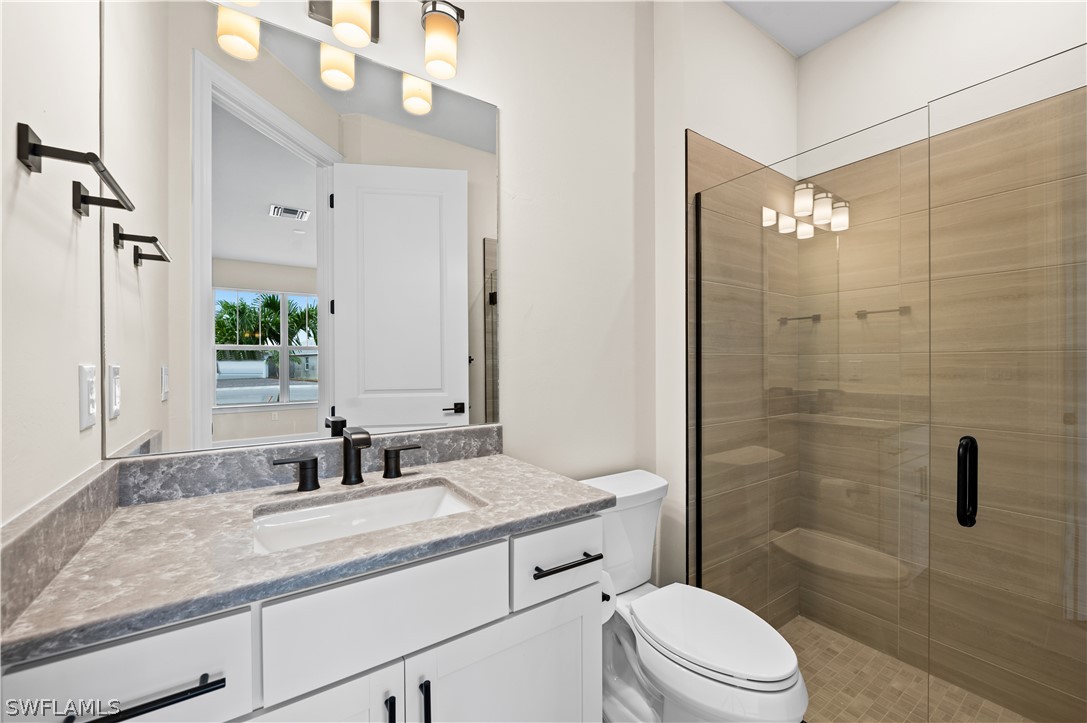42548 Little Ridge Road Punta Gorda, FL 33982 - Photo 27 of 50 a bathroom with a granite countertop sink a toilet a mirror and shower