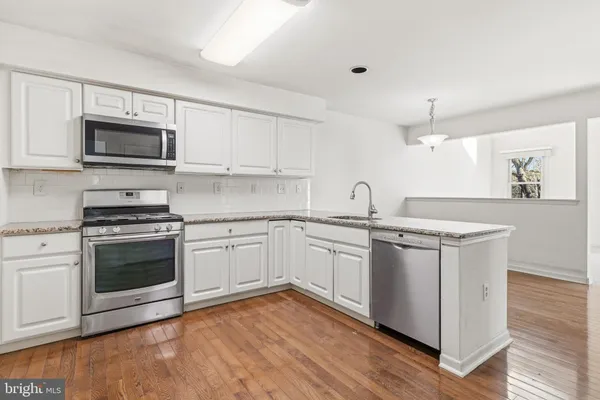 a kitchen with stainless steel appliances granite countertop a stove top oven a sink and white cabinets
