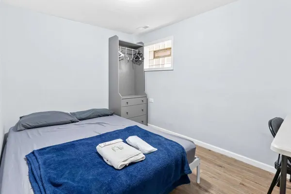 a bed sitting in a bedroom next to a window with wooden floor