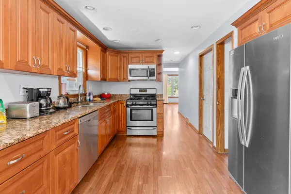 a kitchen with stainless steel appliances granite countertop a refrigerator a stove top oven a sink and dishwasher with wooden floor
