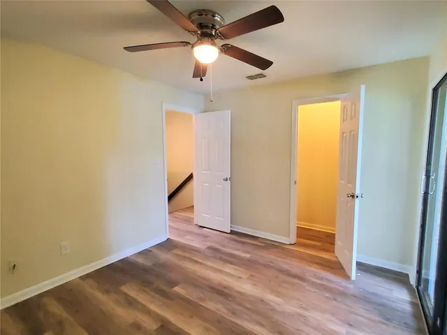 an empty room with wooden floor and a ceiling fan