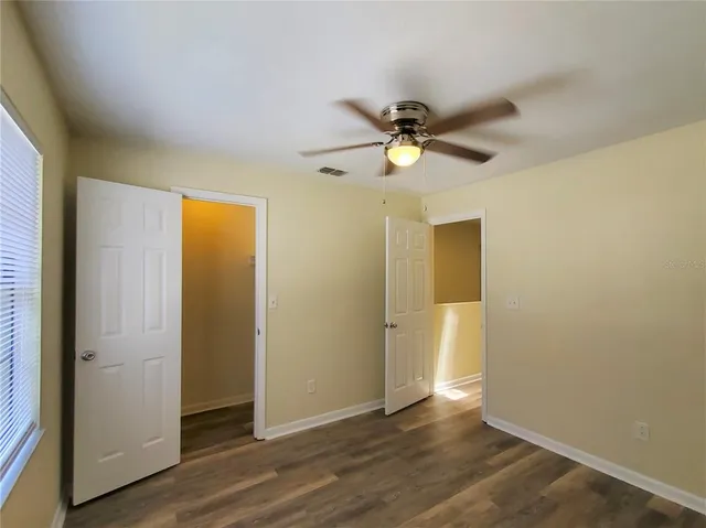 an empty room with wooden floor and a ceiling fan