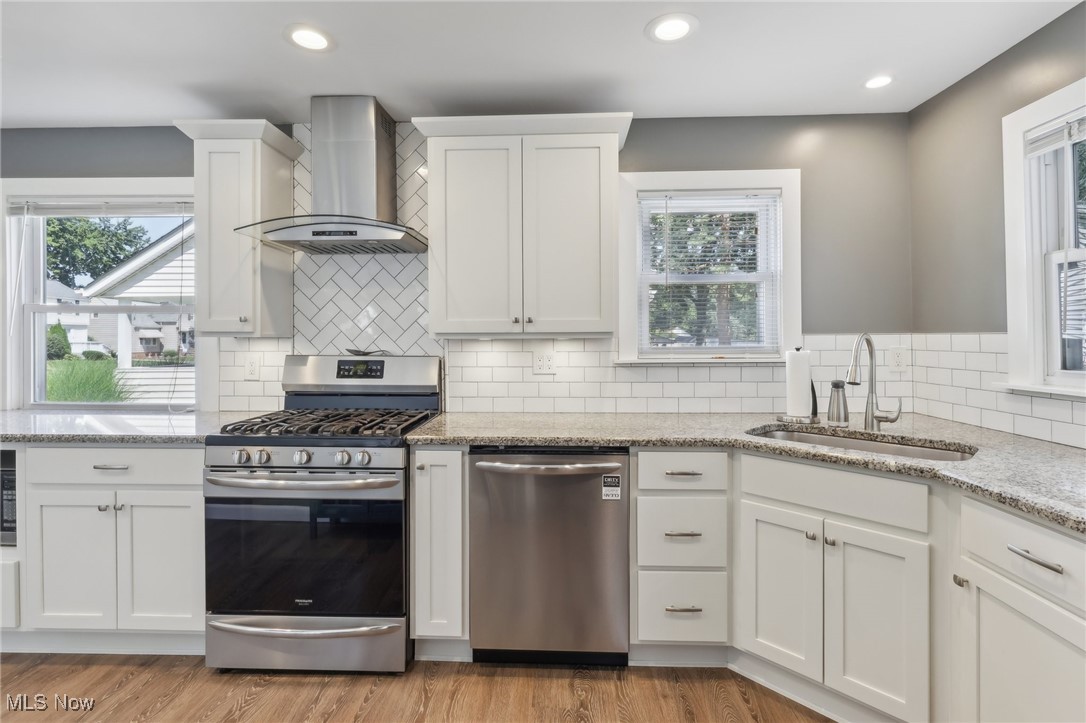1567 Roselawn Road Cleveland, OH 44124 - Photo 4 of 29 Kitchen with tasteful backsplash, appliances with stainless steel finishes, light hardwood / wood-style flooring, sink, and wall chimney exhaust hood