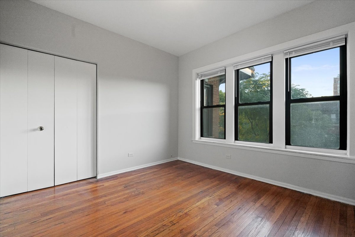 6700 South Merrill Avenue, Unit 3E Chicago, IL 60649 - Photo 3 of 12 a view of an empty room with wooden floor and a window