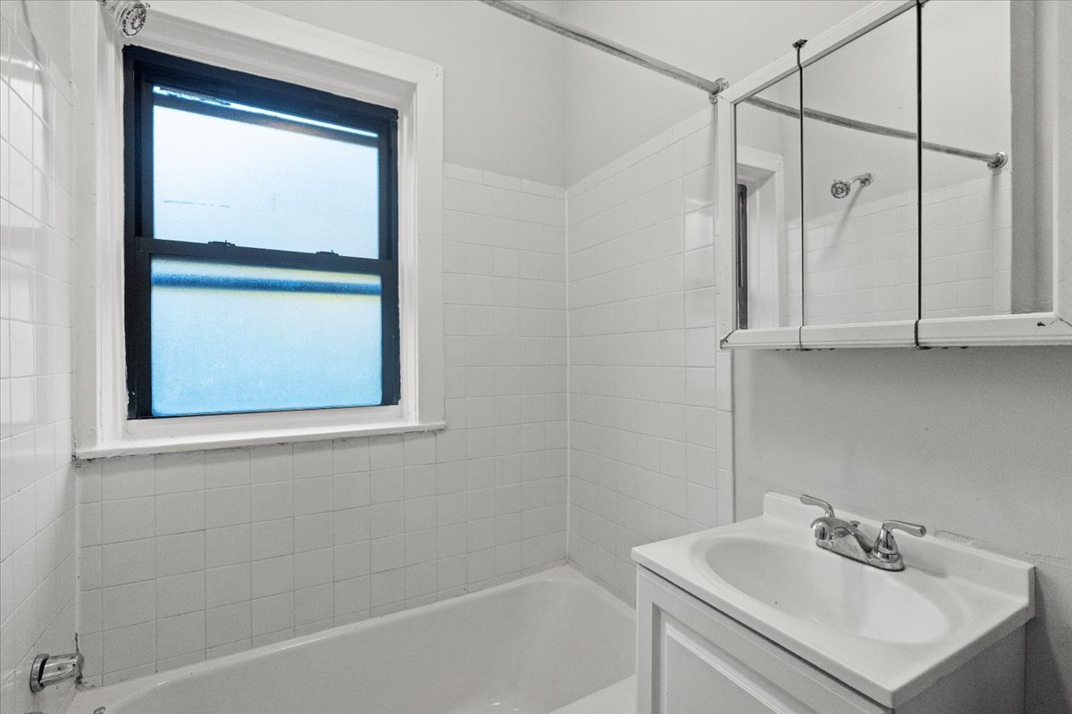 6700 South Merrill Avenue, Unit 3E Chicago, IL 60649 - Photo 5 of 12 a white bath tub sitting next to a white sink and a shower