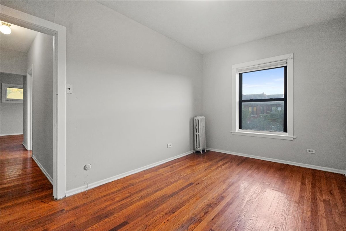 6700 South Merrill Avenue, Unit 3E Chicago, IL 60649 - Photo 6 of 12 a view of an empty room with wooden floor and a window