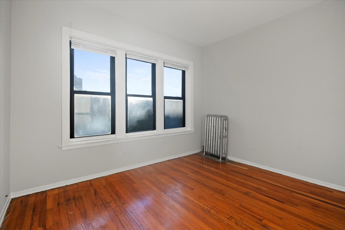 6700 South Merrill Avenue, Unit 3E Chicago, IL 60649 - Photo 9 of 12 a view of an empty room with wooden floor and a window