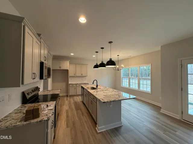 a kitchen with stainless steel appliances granite countertop a sink dishwasher a stove and a refrigerator with wooden floor