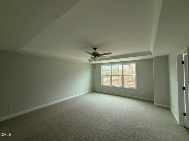 an empty room with a chandelier fan and windows