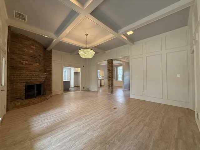 a view of an empty room with wooden floor and a fireplace