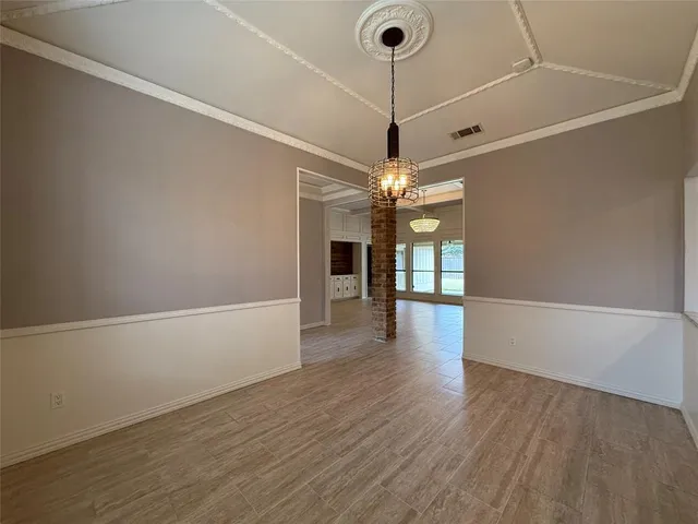 a view of an empty room with wooden floor kitchen and a window