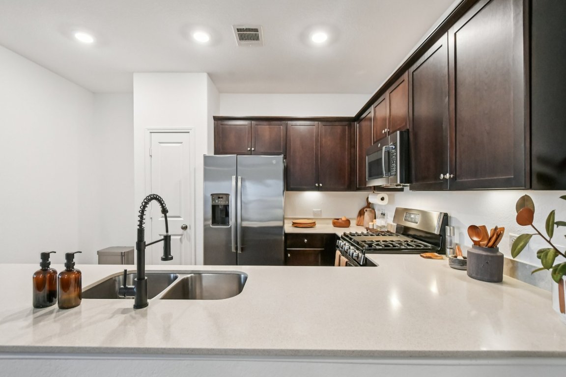117 Badillo Way Bastrop, TX 78602 - Photo 20 of 40 a kitchen with stainless steel appliances a sink a stove and a refrigerator with wooden floor