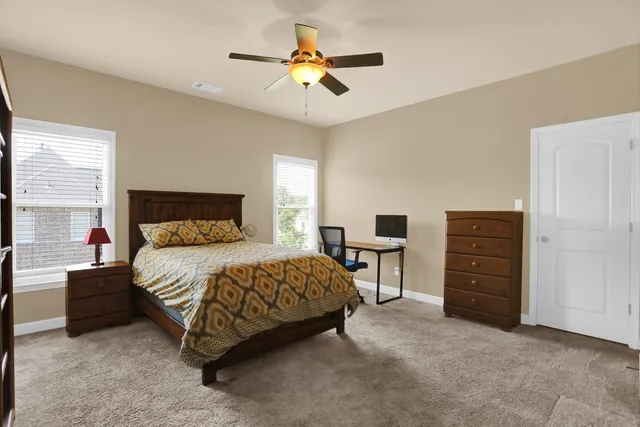 an empty room with chandelier fan and windows