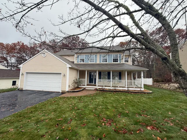 a front view of a house with a yard and large trees