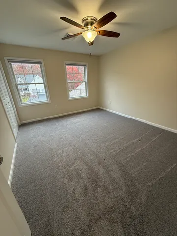 a view of an empty room with wooden floor and kitchen