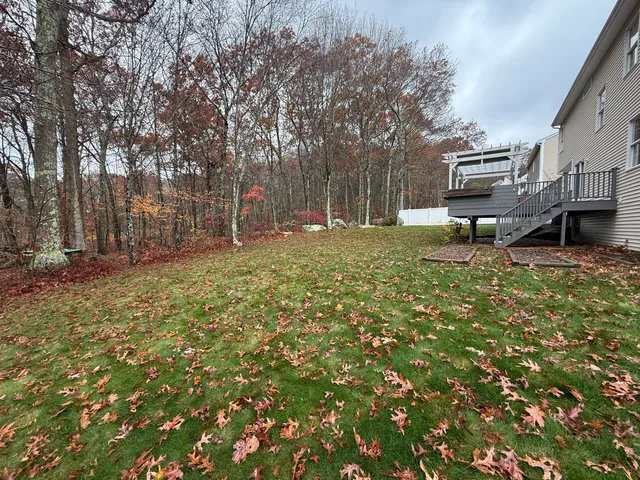 a view of a brick house with large trees and wooden fence