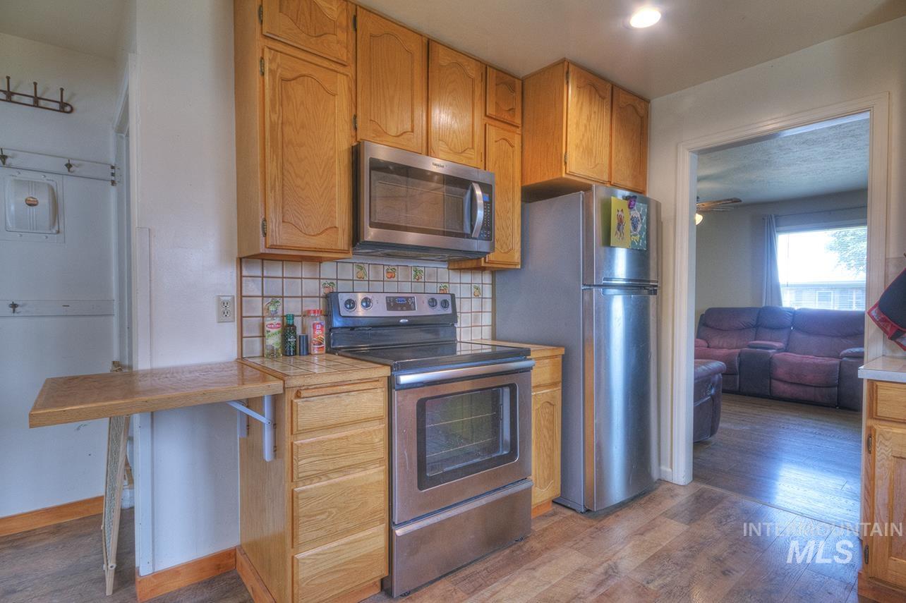 351 West Main Street South Vale, OR 97918 - Photo 6 of 33 Kitchen featuring light wood cabinetry, stainless steel appliances, a tile backsplash, and wood-finish flooring