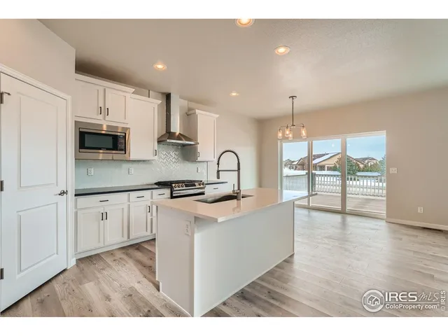 a kitchen with stainless steel appliances granite countertop a sink a stove a microwave a center island and a window