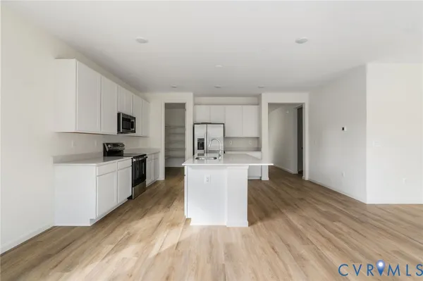 a kitchen with stainless steel appliances a microwave a stove a sink dishwasher and a refrigerator with wooden floor