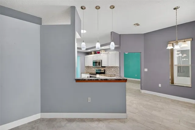 a view of an empty room with window and chandelier fan