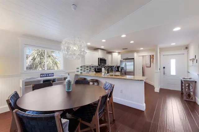a kitchen with a dining table chairs wooden floor appliances and cabinets