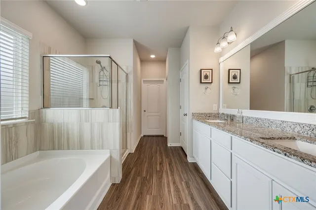 a bathroom with a granite countertop bathtub a sink and a shower