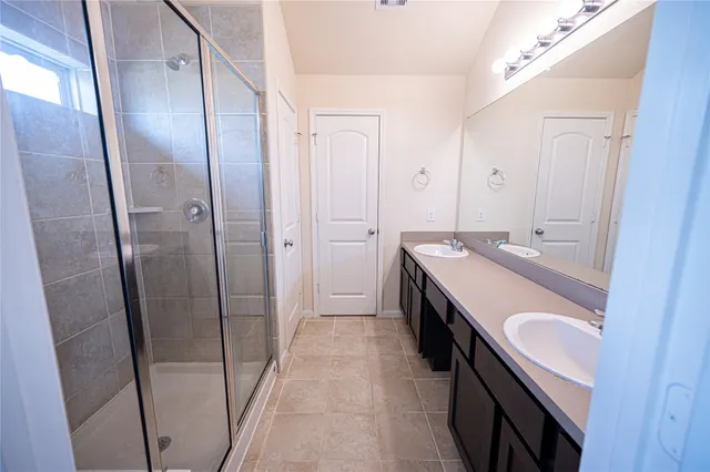 a bathroom with double vanity and a tub