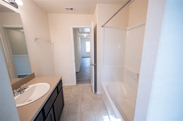 a bathroom with a granite countertop sink a mirror and a bathtub