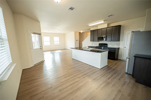 a kitchen with stainless steel appliances granite countertop a stove top oven a sink dishwasher a refrigerator and cabinets with wooden floor