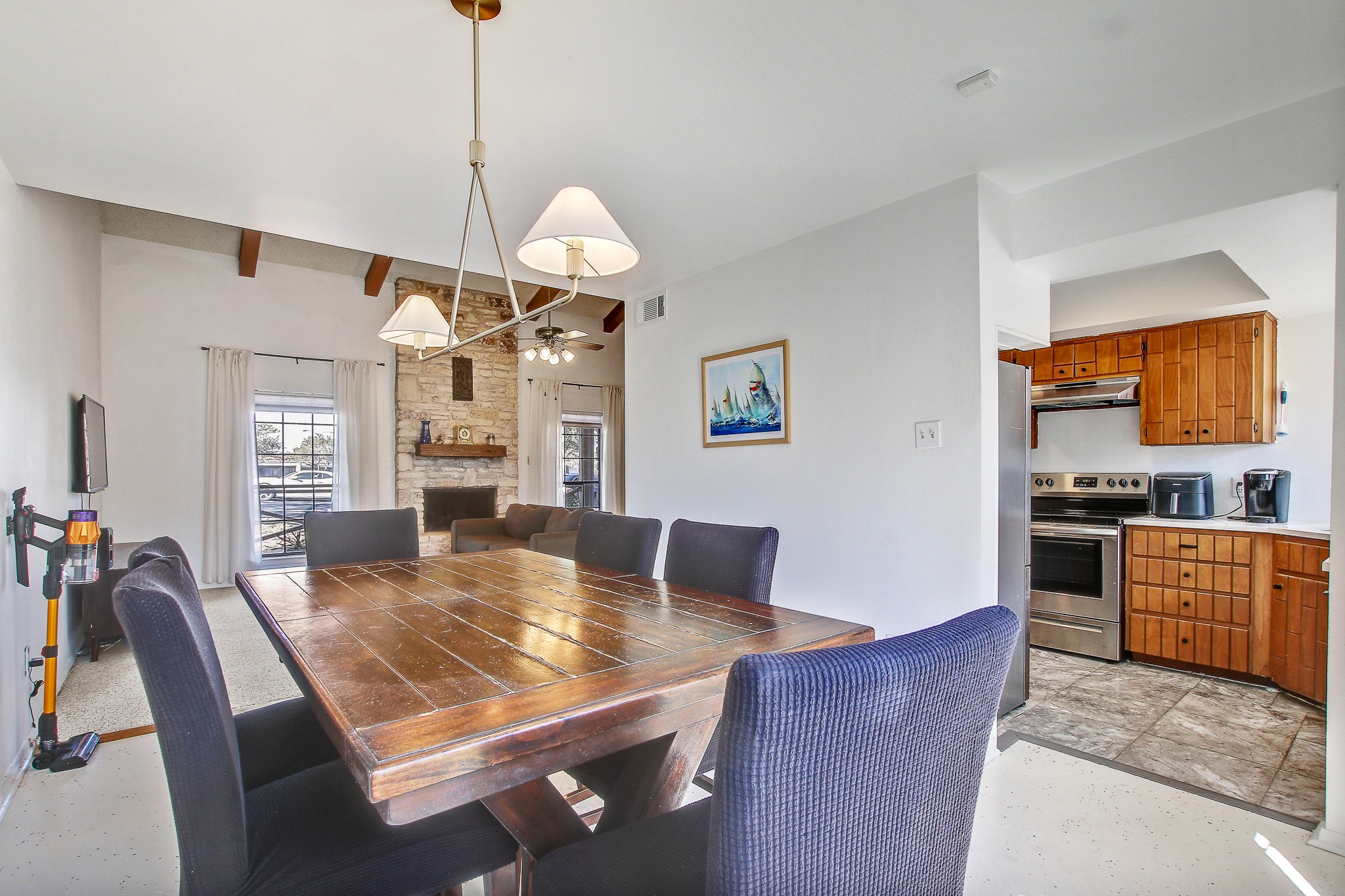 8925 North Plaza, Unit 69 Austin, TX 78753 - Photo 15 of 29 Dining room with a stone fireplace, ceiling fan, and beamed ceiling