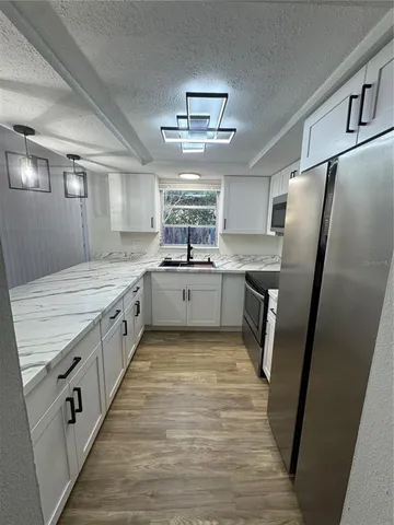 a large kitchen with stainless steel appliances granite countertop a sink stove and refrigerator