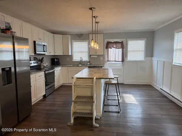 a kitchen with kitchen island a counter top space a sink stainless steel appliances and cabinets