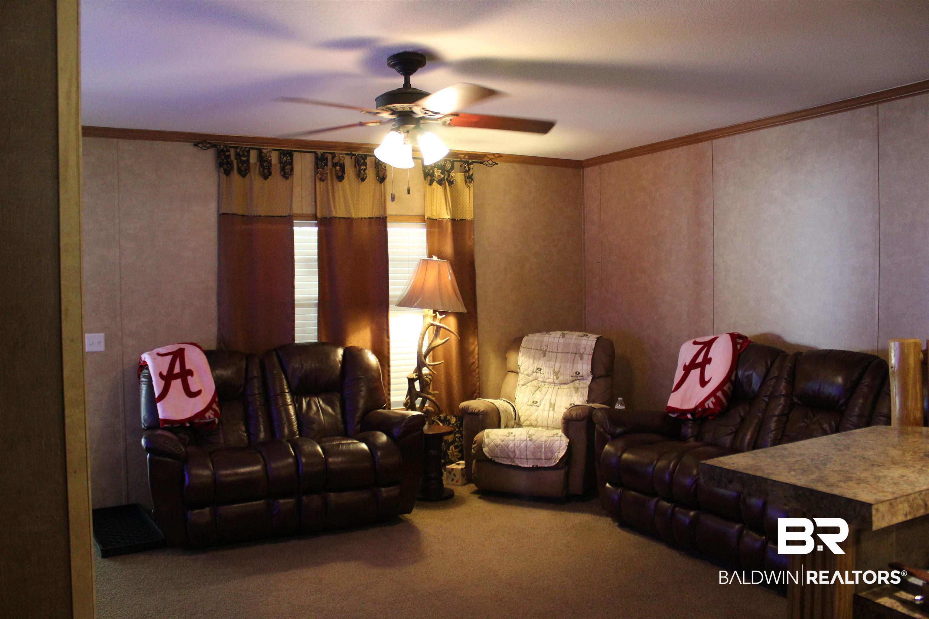 7258 Henderson Road Lowndesboro, AL 36752 - Photo 13 of 22 Carpeted living area featuring ornamental molding and ceiling fan