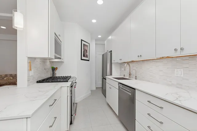 a kitchen with stainless steel appliances granite countertop a sink a stove and a refrigerator