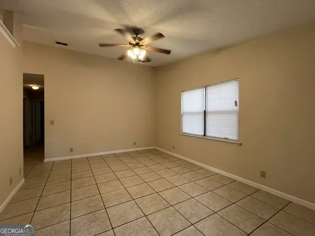 an empty room with chandelier fan and windows