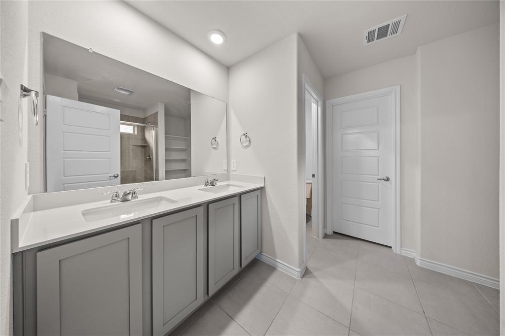 9805 Quail Pointe Road Aubrey, TX 76227 - Photo 16 of 38 Dual vanity with light gray cabinetry, white countertops, and chrome fixtures
