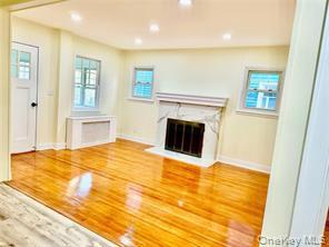 48 Lincoln Street New Rochelle, NY 10801 - Photo 3 of 9 Unfurnished living room featuring healthy amount of natural light, baseboards, a high end fireplace, wood finished floors, and recessed lighting