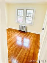 48 Lincoln Street New Rochelle, NY 10801 - Photo 5 of 9 Empty room featuring radiator, baseboards, and wood finished floors