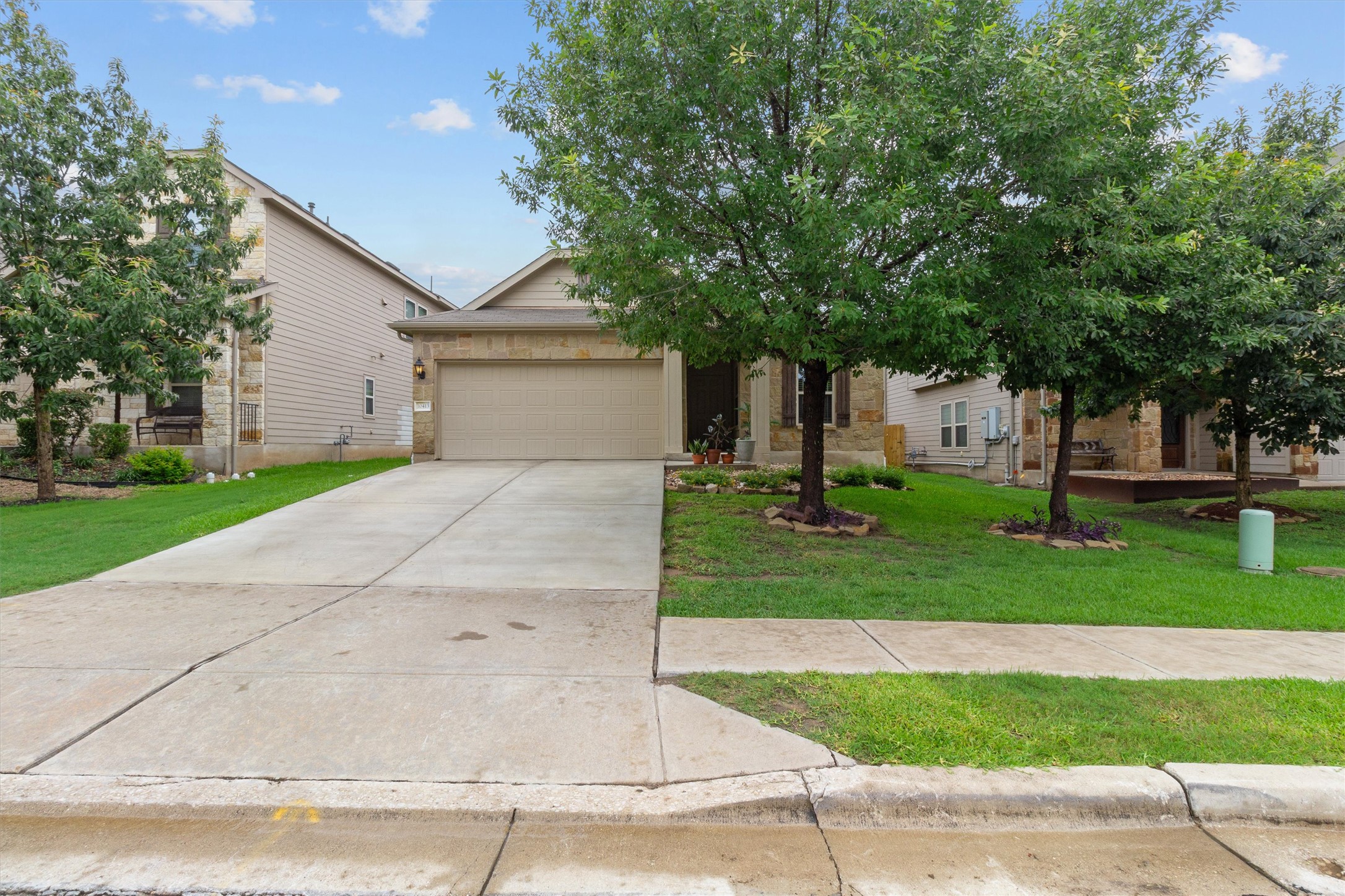 10413 Crescendo Lane Austin, TX 78747 - Photo 28 of 32 A well-maintained suburban home featuring a concrete driveway and mature trees in the front yard.