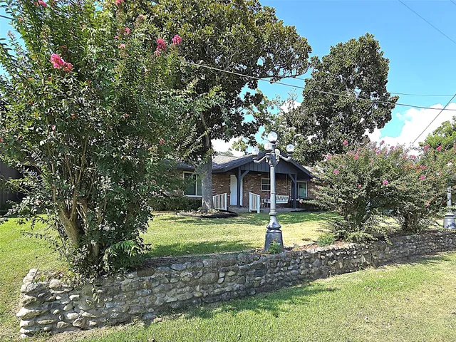 a view of a house with a small yard and a large tree