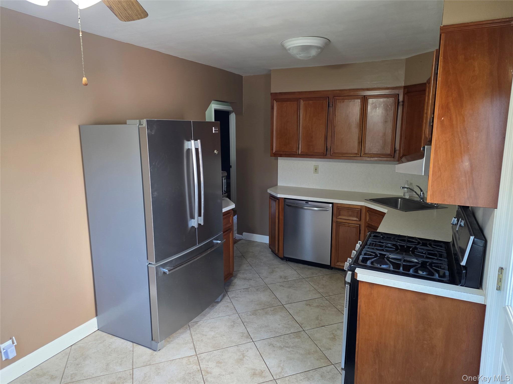 220 Raff Avenue Mineola, NY 11501 - Photo 2 of 22 Kitchen featuring stainless steel appliances, light countertops, brown cabinetry, light tile patterned flooring, and ceiling fan
