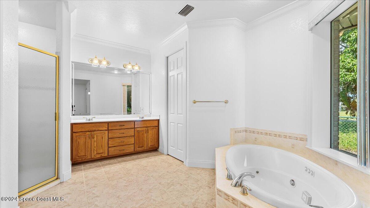 9140 South Tropical Trail Merritt Island, FL 32952 - Photo 21 of 68 a bathroom with a tub a sink and a large mirror