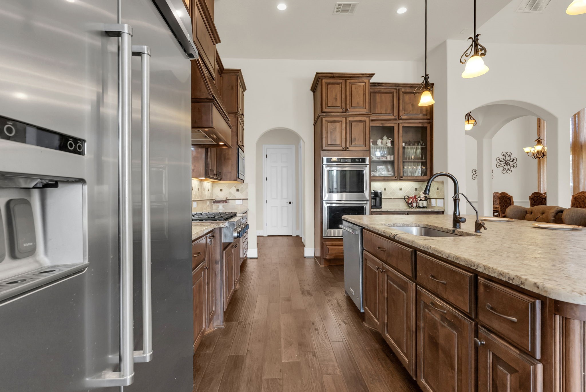 4022 Sabine Valley Trail Spring, TX 77386 - Photo 11 of 46 This modern kitchen features stainless steel appliances, rich wooden cabinetry, and a spacious island with a sink. It has elegant lighting and an open layout, perfect for entertaining.