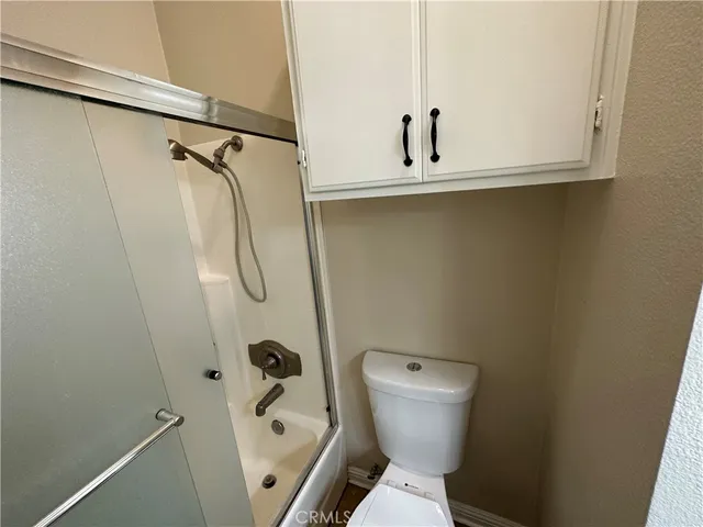 an empty room with wooden floor chandelier and windows