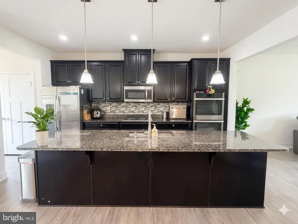 a kitchen with kitchen island granite countertop a sink a counter space appliances and cabinets