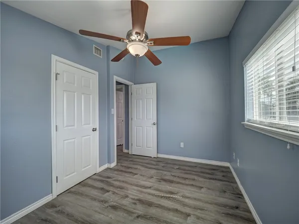 a view of an empty room with wooden floor and window