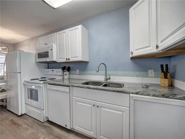 a kitchen with granite countertop white cabinets and white appliances