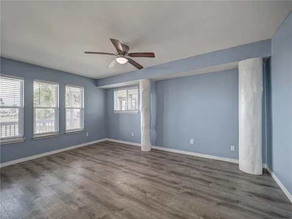 a view of empty room with wooden floor and fan