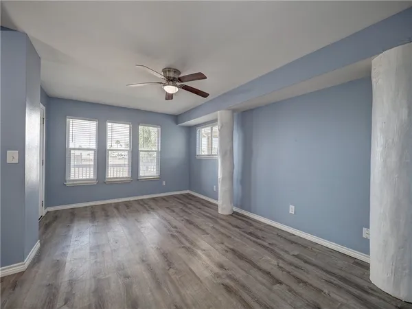 a view of an empty room with a window and wooden floor